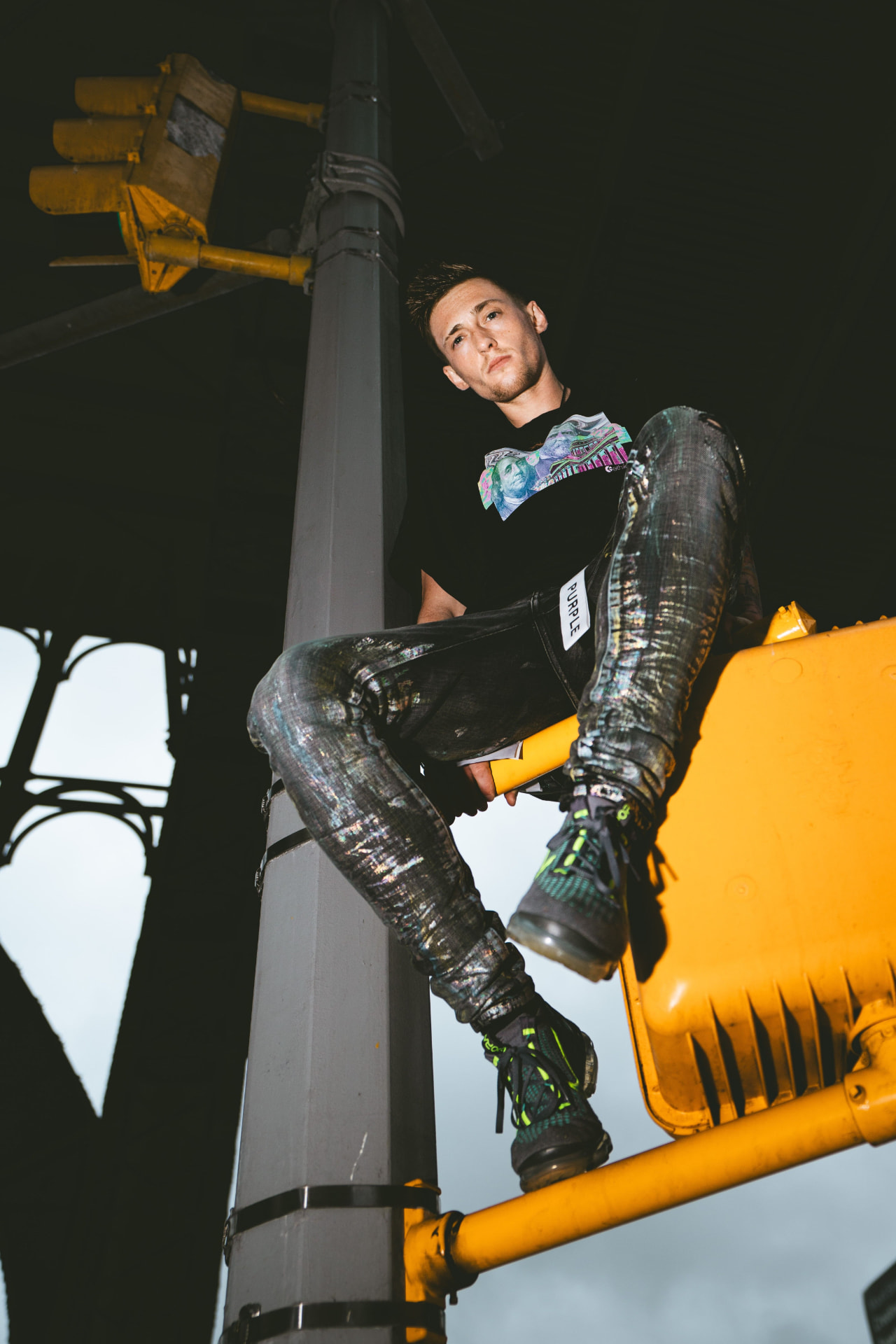 Kaden Quinn perched on a yellow NYC traffic signal arm shot from below at dusk