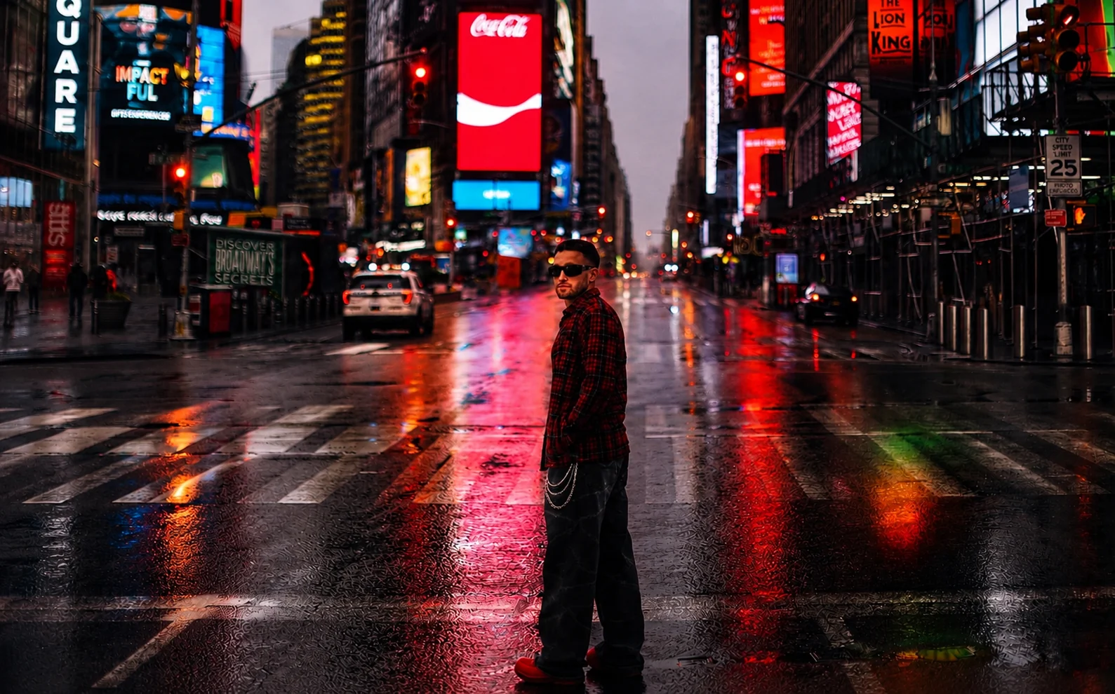 Kaden Quinn in a red flannel shirt and sunglasses standing in rain-soaked Times Square at night surrounded by billboards